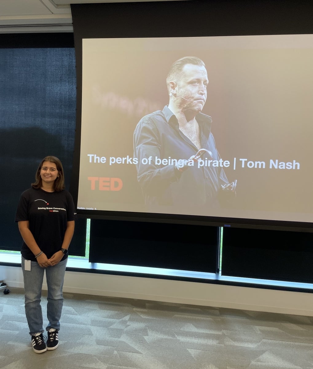 Grace Brignola by a screen showing a TED Talk, at Subaru