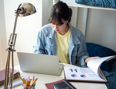 image of female student studying on laptop in her room