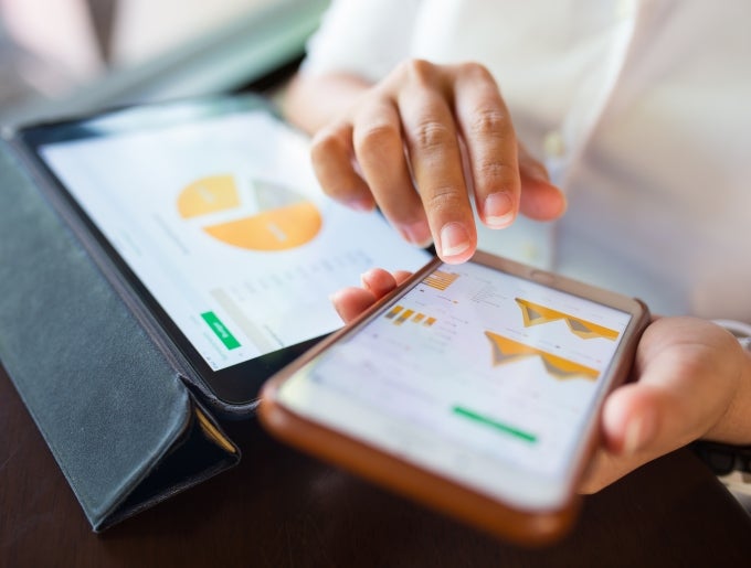 image of person using tablet and phone for data analysis