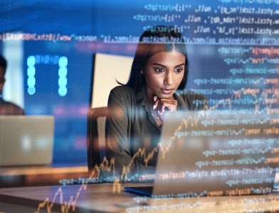 young woman on laptop searching computer code for a security bug